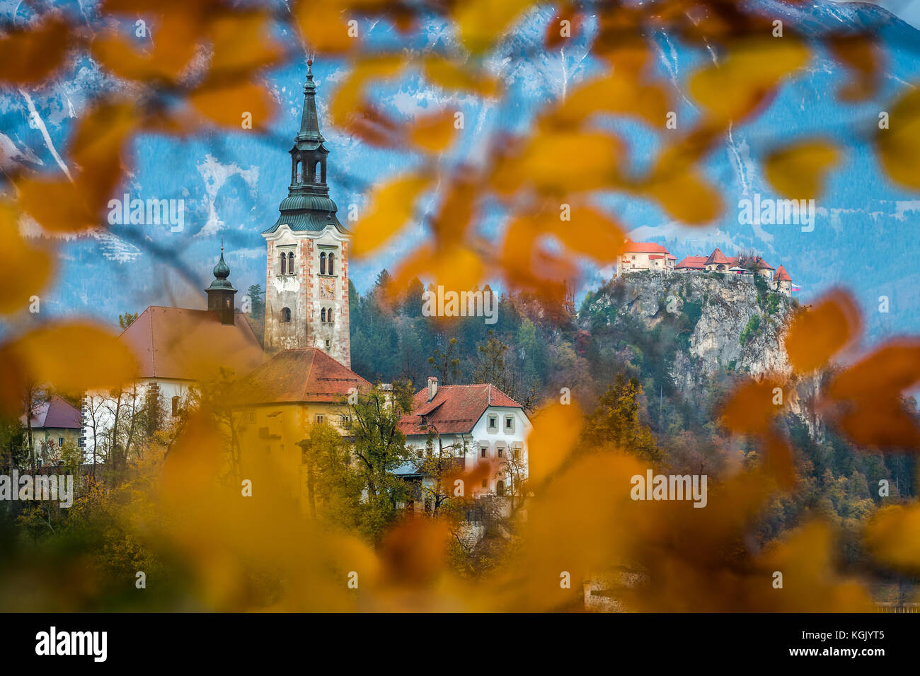 Bled, Slovenia - Beautiful autumn foliage framed Pilgrimage Church of the Assumption of Maria with Bled Castle and Julian Alps at background Stock Photo