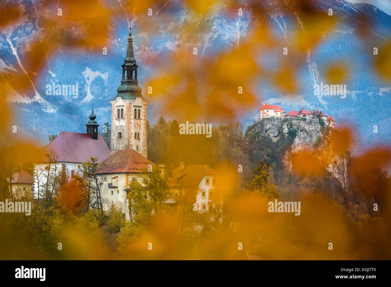 Bled, Slovenia - Beautiful autumn foliage framed Pilgrimage Church of the Assumption of Maria with Bled Castle and Julian Alps at background Stock Photo