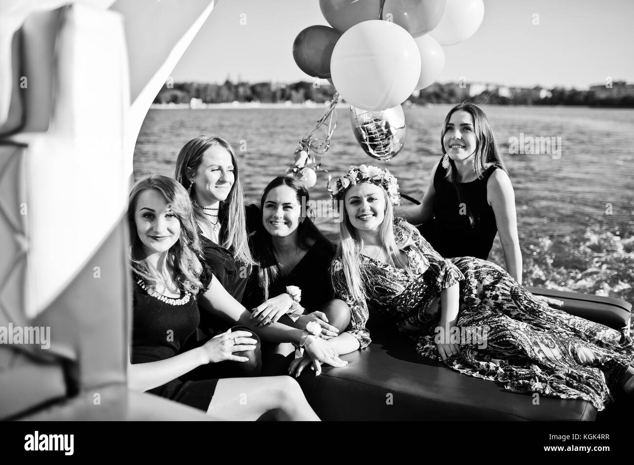 Five girls wear on black having fun at yacht against lake at hen party. Stock Photo