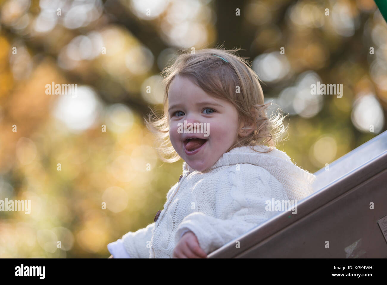 18 month old child playing on a slide in a park, UK Stock Photo