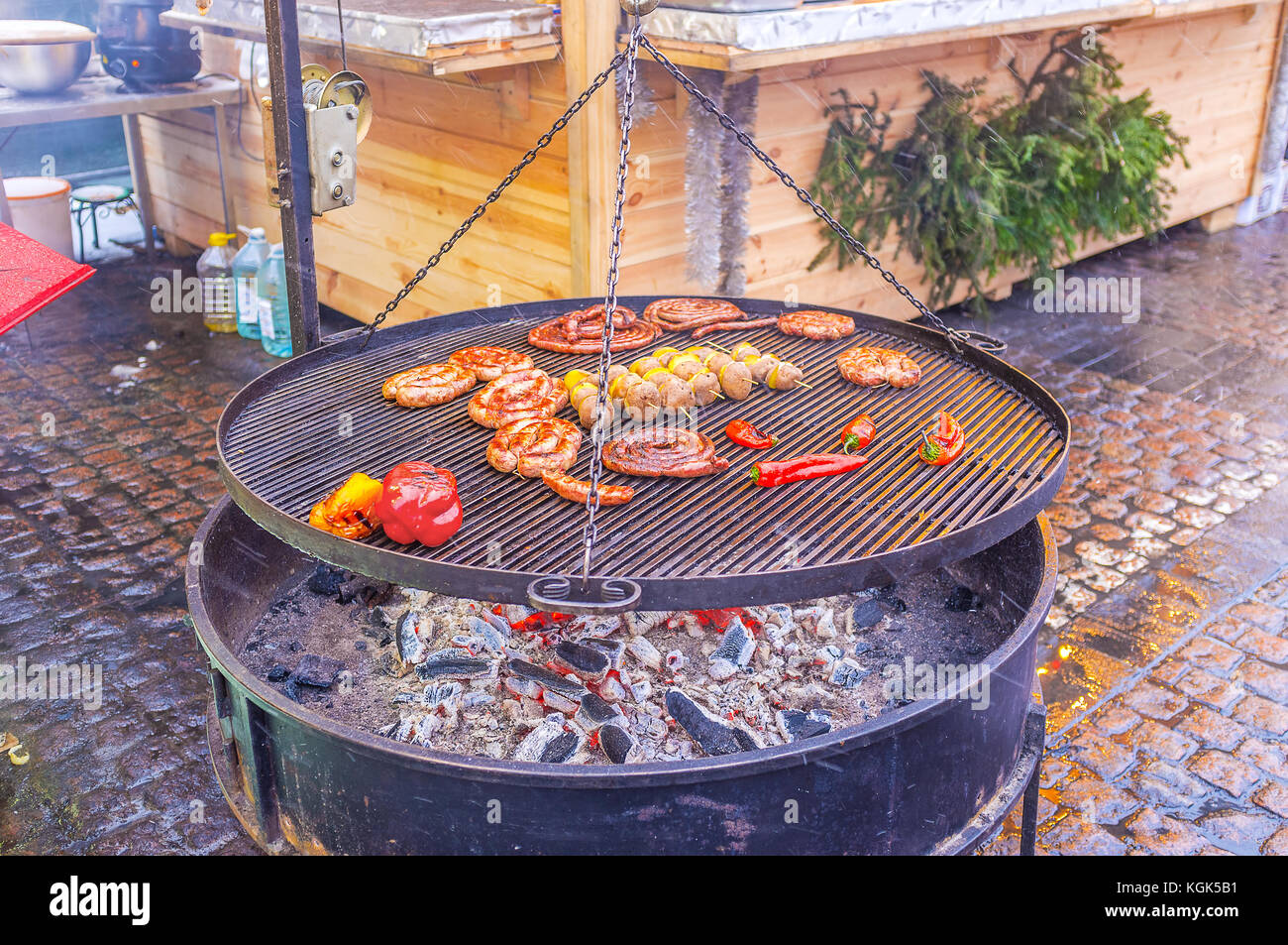 The cold winter evening is the best time to taste hot grilled sausages and vegetables with mulled wine at the Christmas Market in Kiev, Ukraine Stock Photo