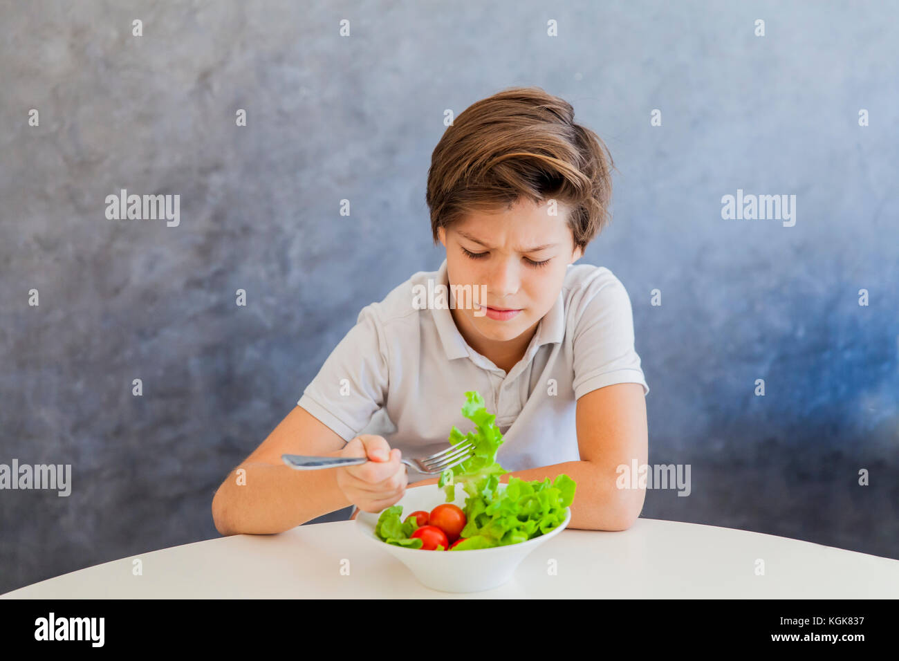 Cute teen boy dont like eating salad Stock Photo - Alamy