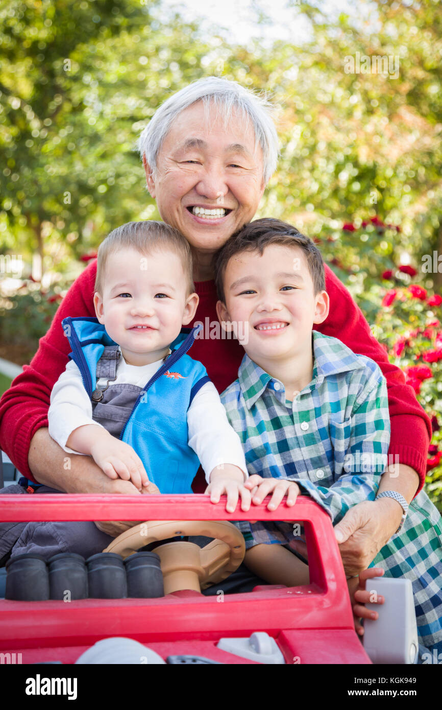 Happy Senior Adult Chinese Man Playing with His Mixed Race Grandchildren Stock Photo