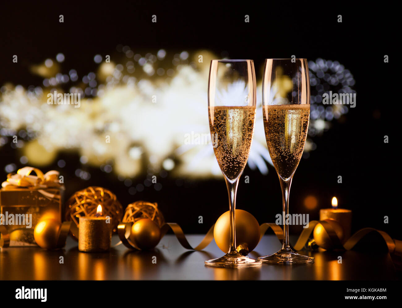 two champagne glasses against holiday lights and fireworks - new year ...