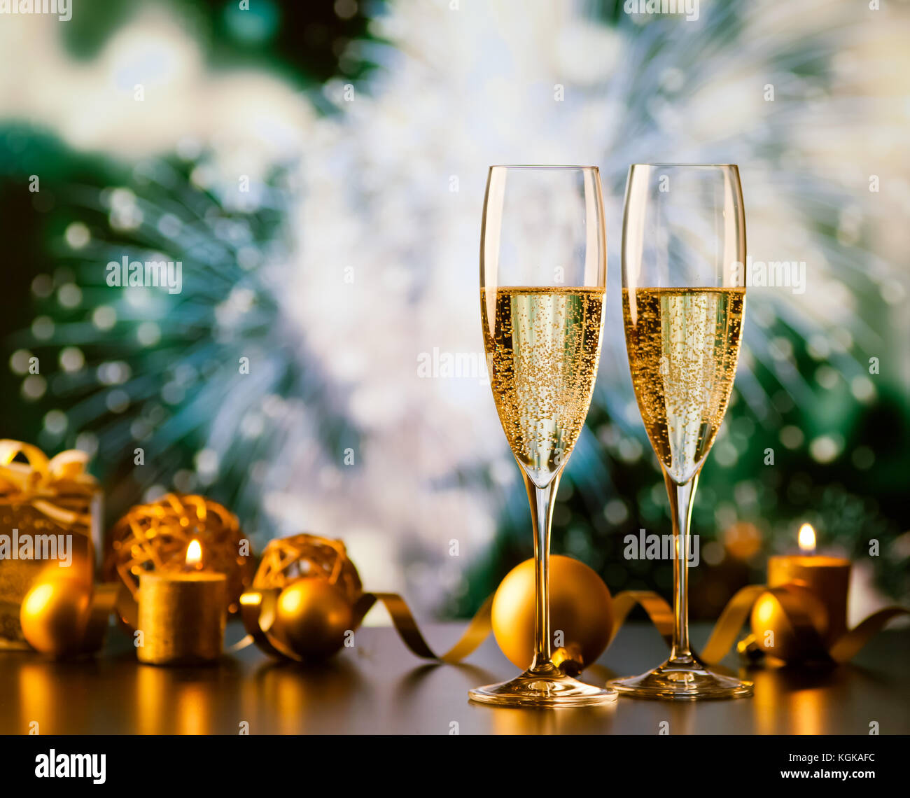 two champagne glasses against holiday lights and fireworks - new year ...