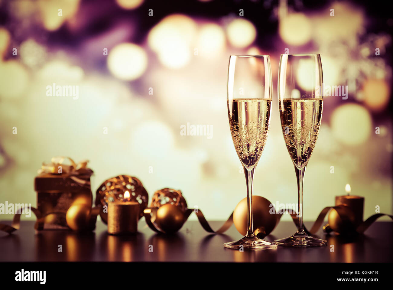 two champagne glasses against holiday lights and fireworks - new year ...