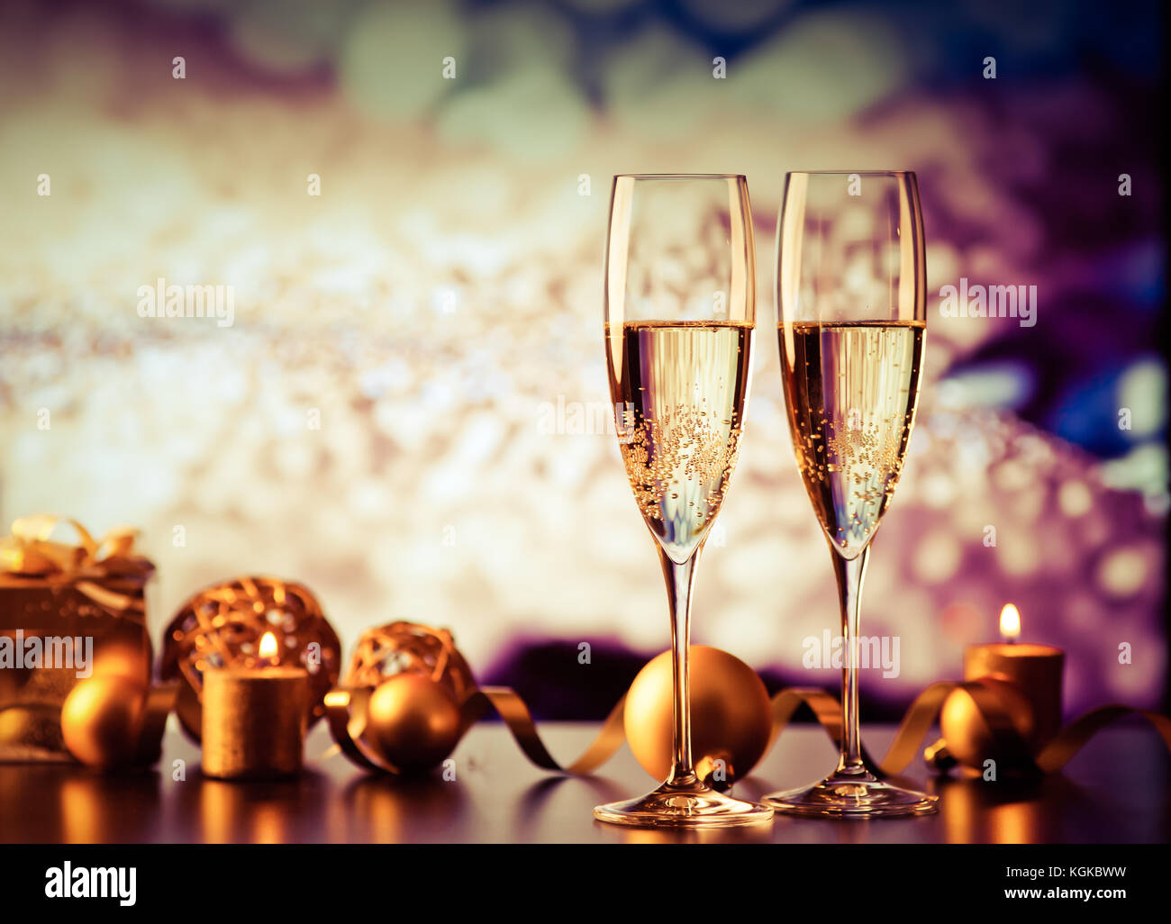 two champagne glasses against holiday lights and fireworks - new year ...