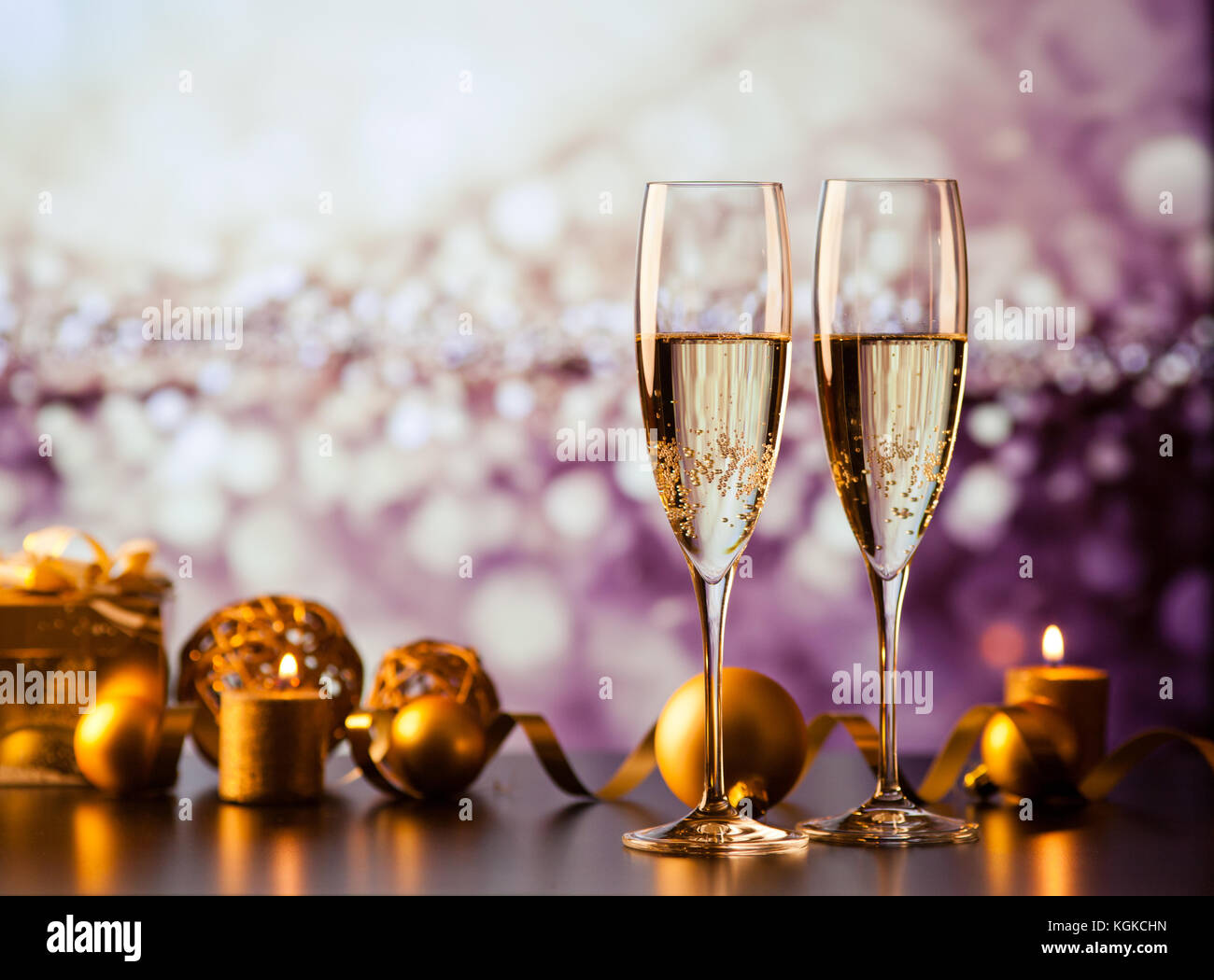 two champagne glasses against holiday lights and fireworks - new year ...