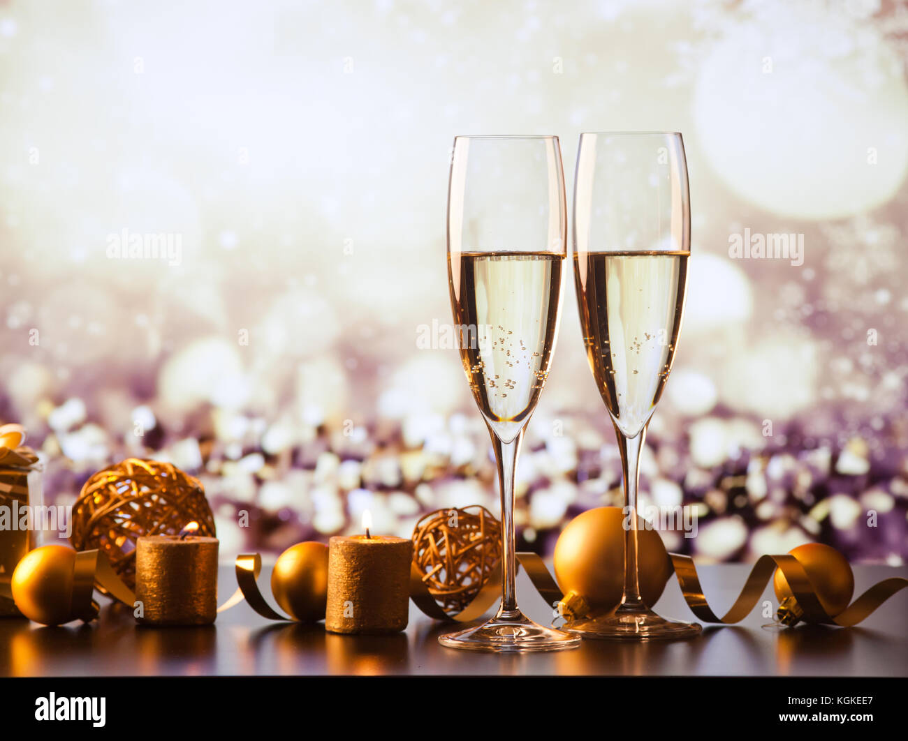 two champagne glasses against holiday lights and fireworks - new year ...