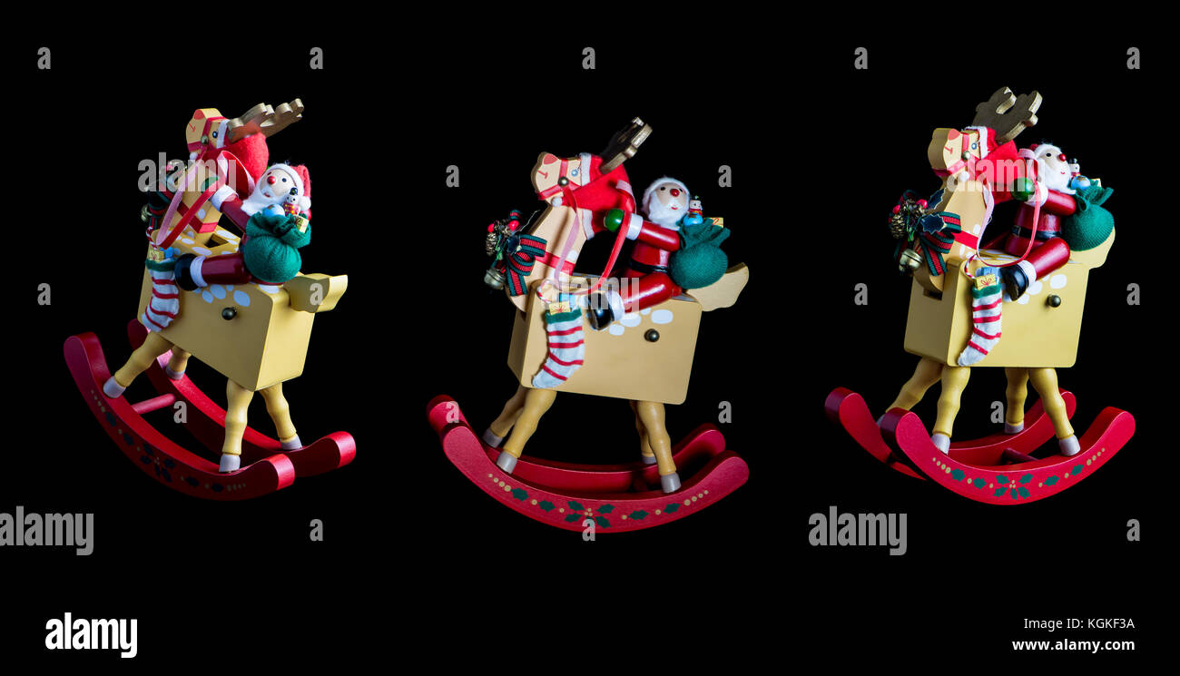 Christmas decorations depicting three rocking Santas, riding their rocking reindeers. Isolated on a dark black isolating background Stock Photo
