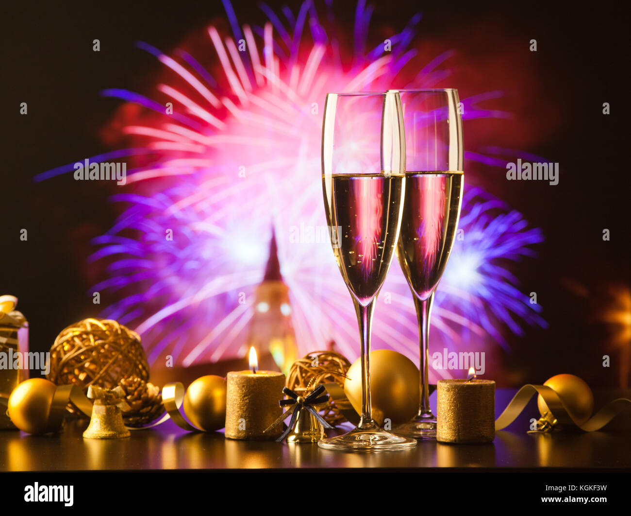 two champagne glasses against holiday lights and fireworks - new year celebration Stock Photo