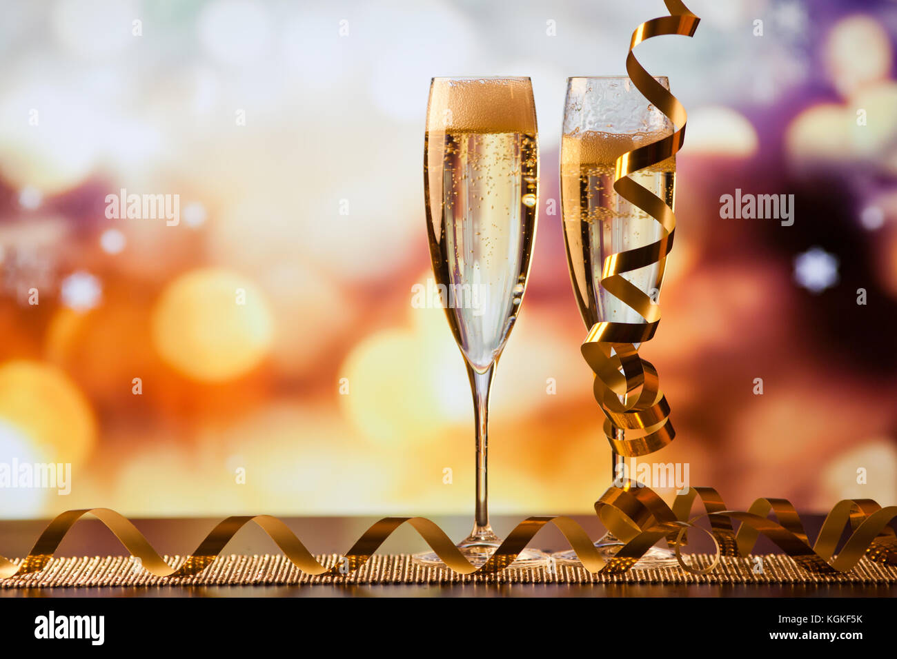 two champagne glasses against holiday lights and fireworks - new year ...