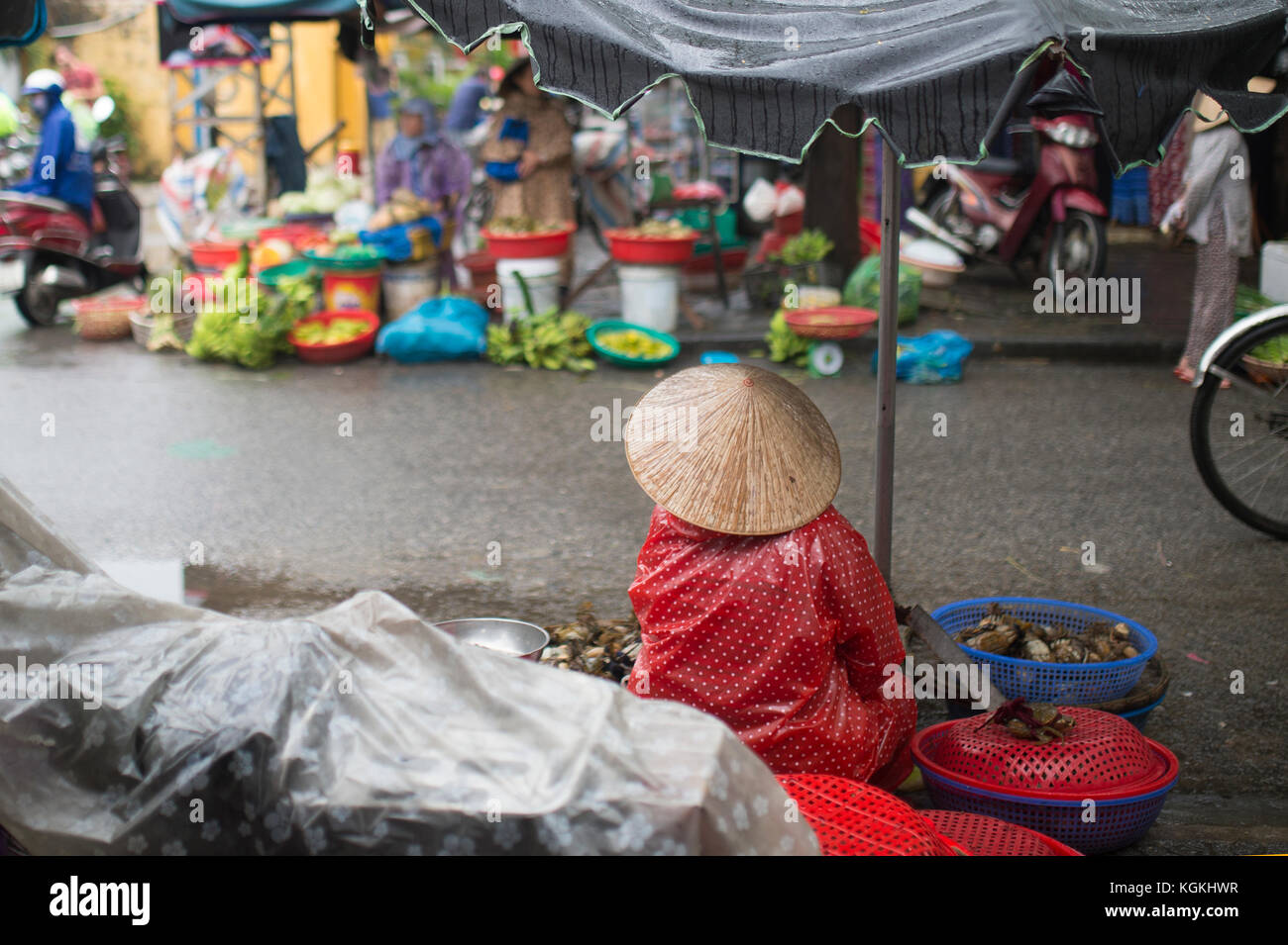 -Selective focus- Unidentified woman with typical vietnamese conical hats sell fresh vegetables on a street market in Hoi An, Vietnam Stock Photo