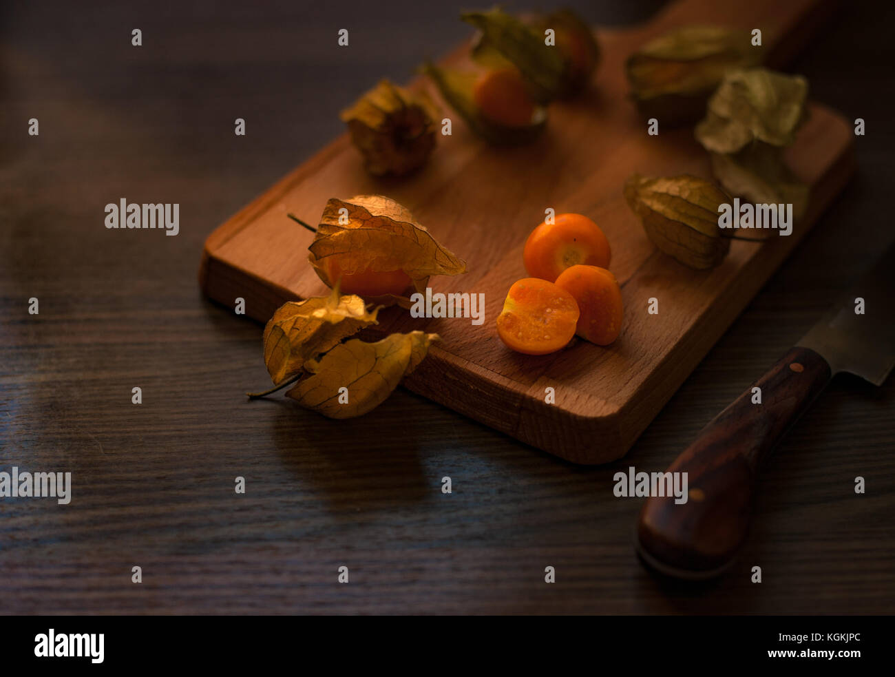 Physalis on a wooden board with kaki fruits and squash. Stock Photo