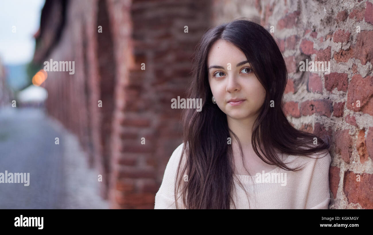 https://c8.alamy.com/comp/KGKMGY/portrait-of-a-young-woman-against-a-medieval-brick-wall-in-europe-KGKMGY.jpg