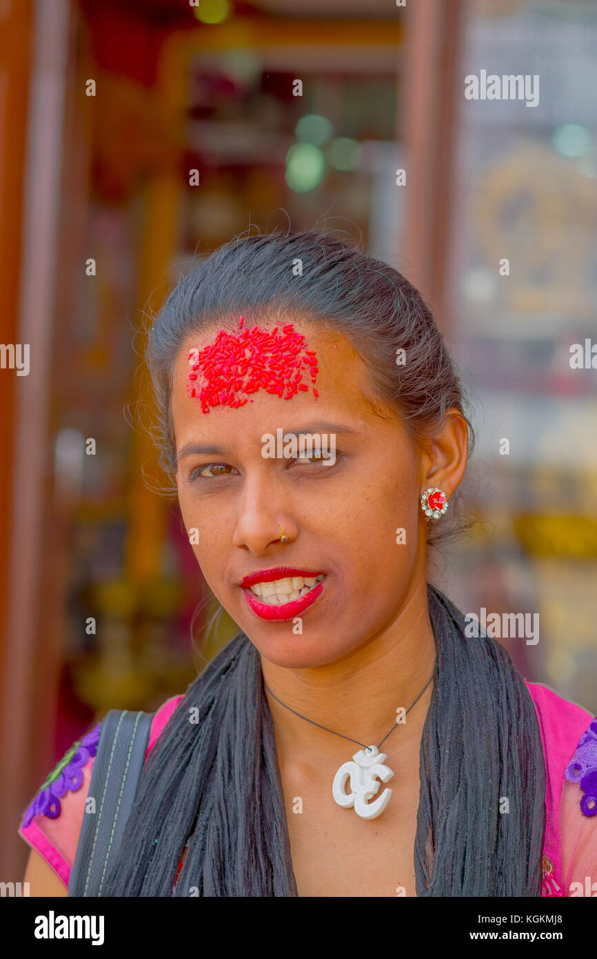 KATHMANDU, NEPAL OCTOBER 15, 2017: Portrait of women in traditional dress with red pieces of rice in her forehead, in Kathmandu, Nepal in a blurred background Stock Photo
