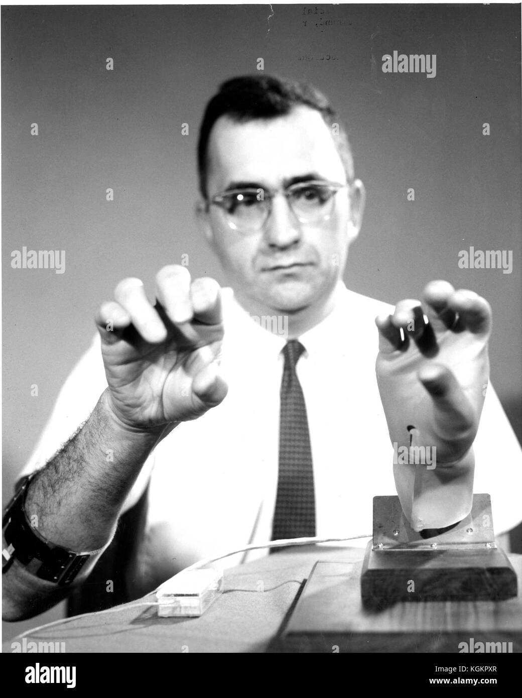 Shoulders up candid photograph of electrical engineer Howard Hoshall with the prosthetic hand in a laboratory, 1969. () Stock Photo