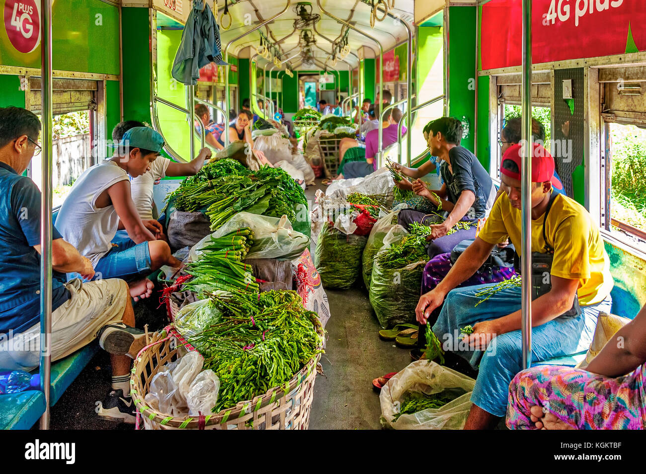 Yangon Circular Line, Myanmar - Oct. 22, 2017: Greengrocers board the train with vegetables in sacks and rattan baskets to cut and trim them on board. Stock Photo