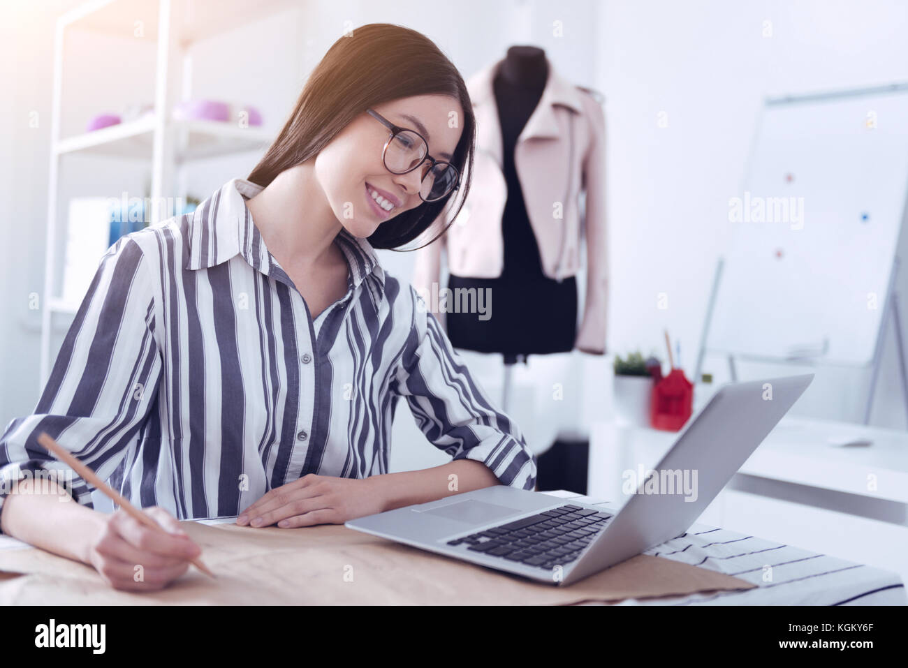 Cheerful young employee looking at the screen of her laptop Stock Photo