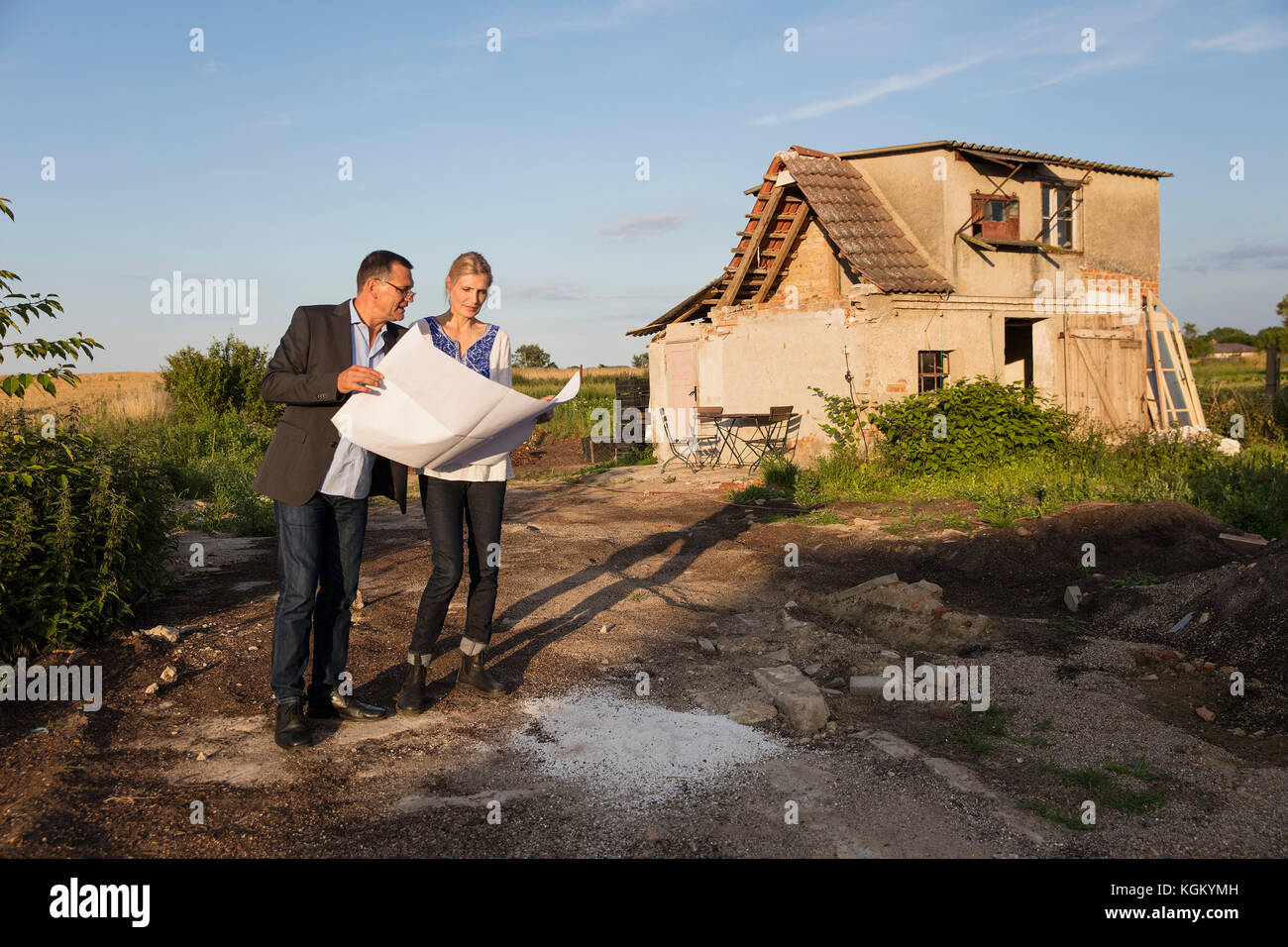 Woman standing with estate agent while reading documents against house on sunny day Stock Photo