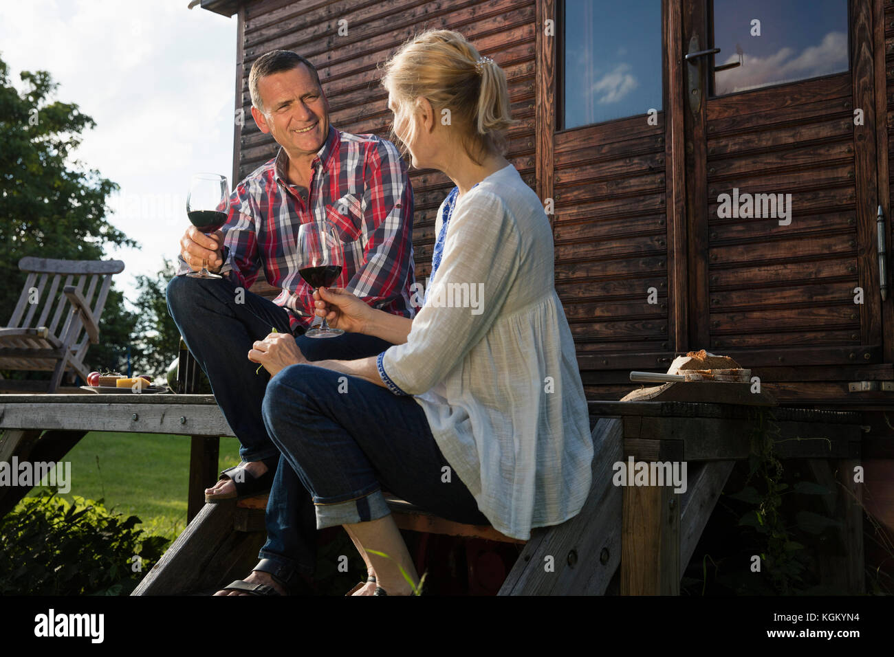 Low angle view of mature couple talking and having wine while resting outside farmhouse Stock Photo