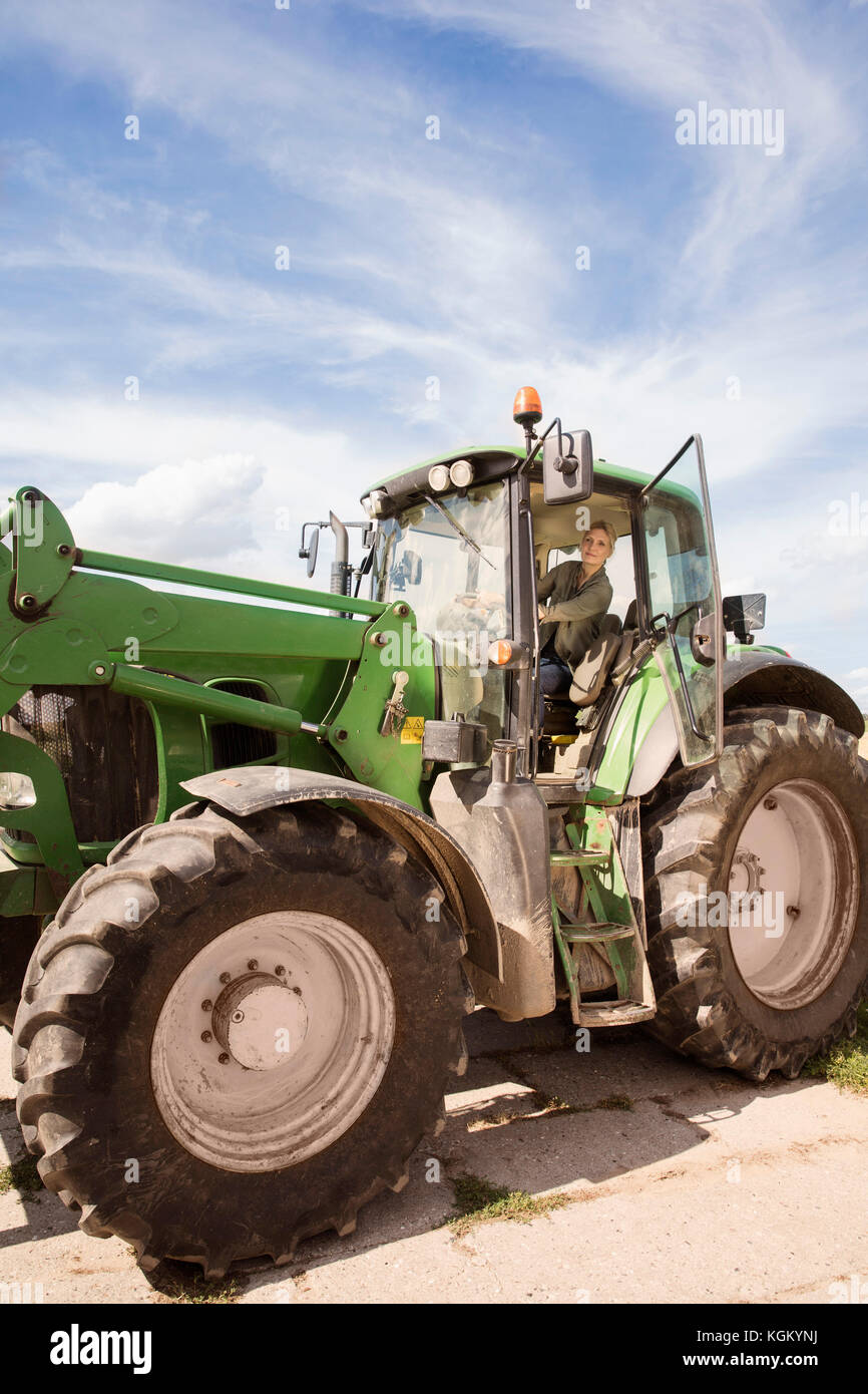 Low angle view of mature woman driving tractor against sky Stock Photo