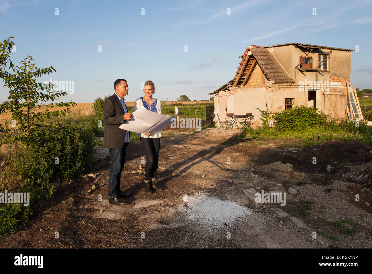 Smiling woman with real estate agent reading document while standing against farmhouse Stock Photo