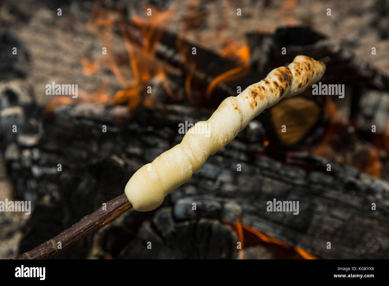 High angle view of dough on wooden skewer over fire Stock Photo