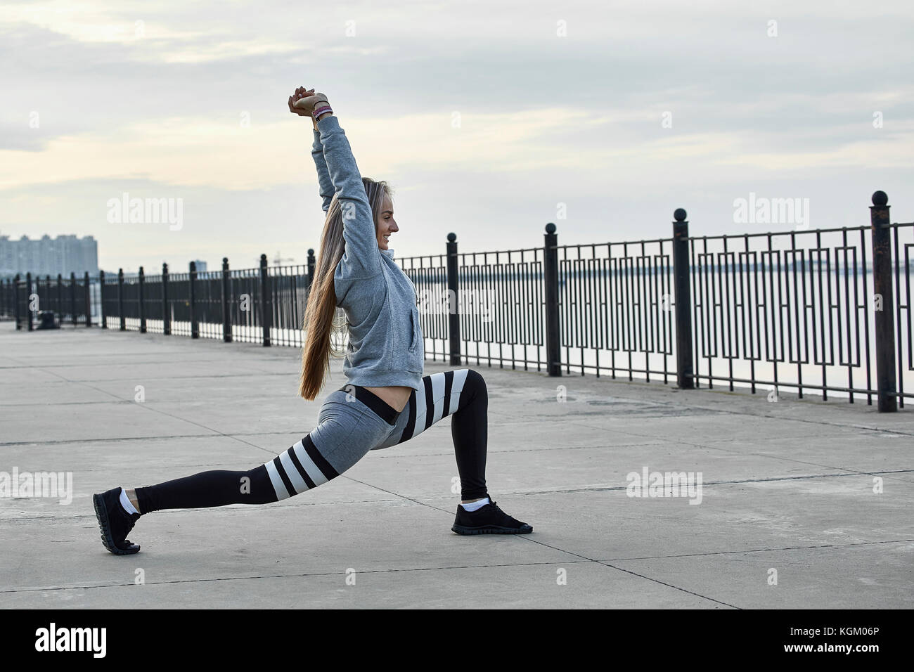Side view of female athlete stretching on promenade Stock Photo