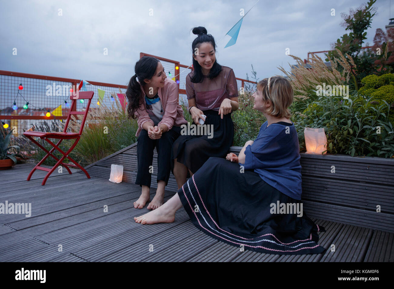 Female friends talking while sitting patio during dusk Stock Photo
