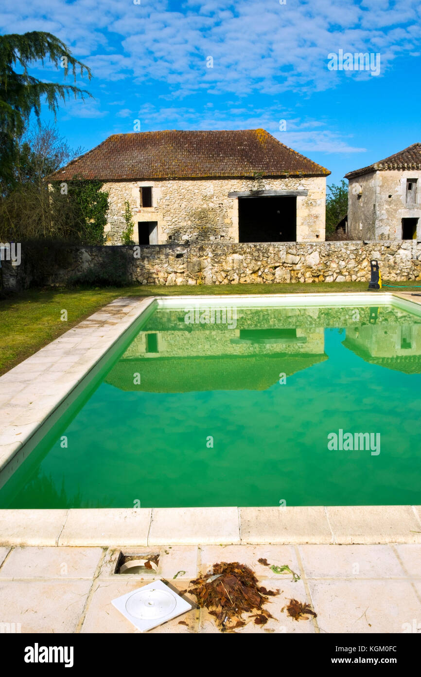 Starting the spring clean up of dead leaves and green algae in a swimming pool neglected over the winter Stock Photo