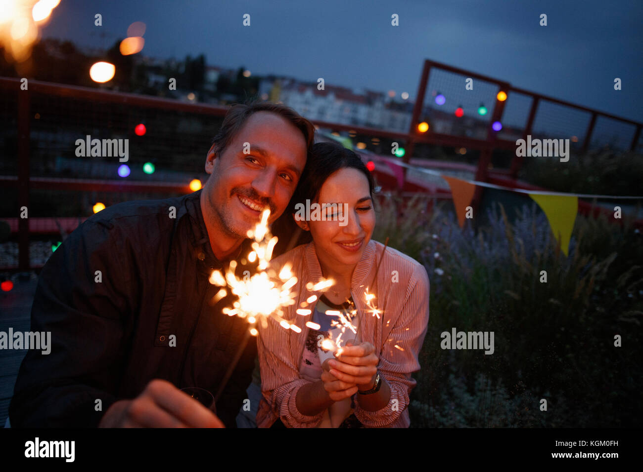 Happy couple holding sparklers on patio at night Stock Photo