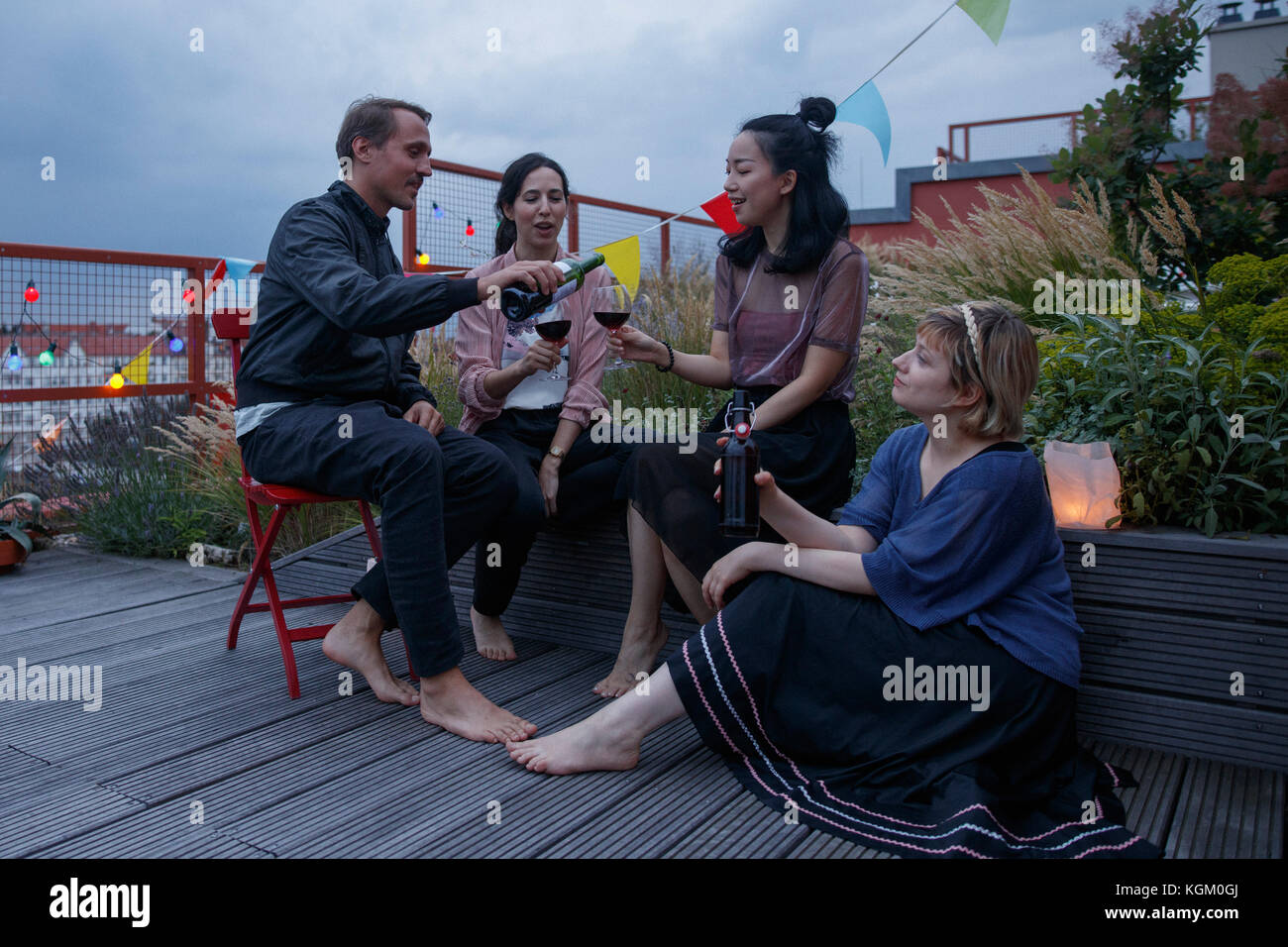 Man serving red wine to female friend during party on patio Stock Photo