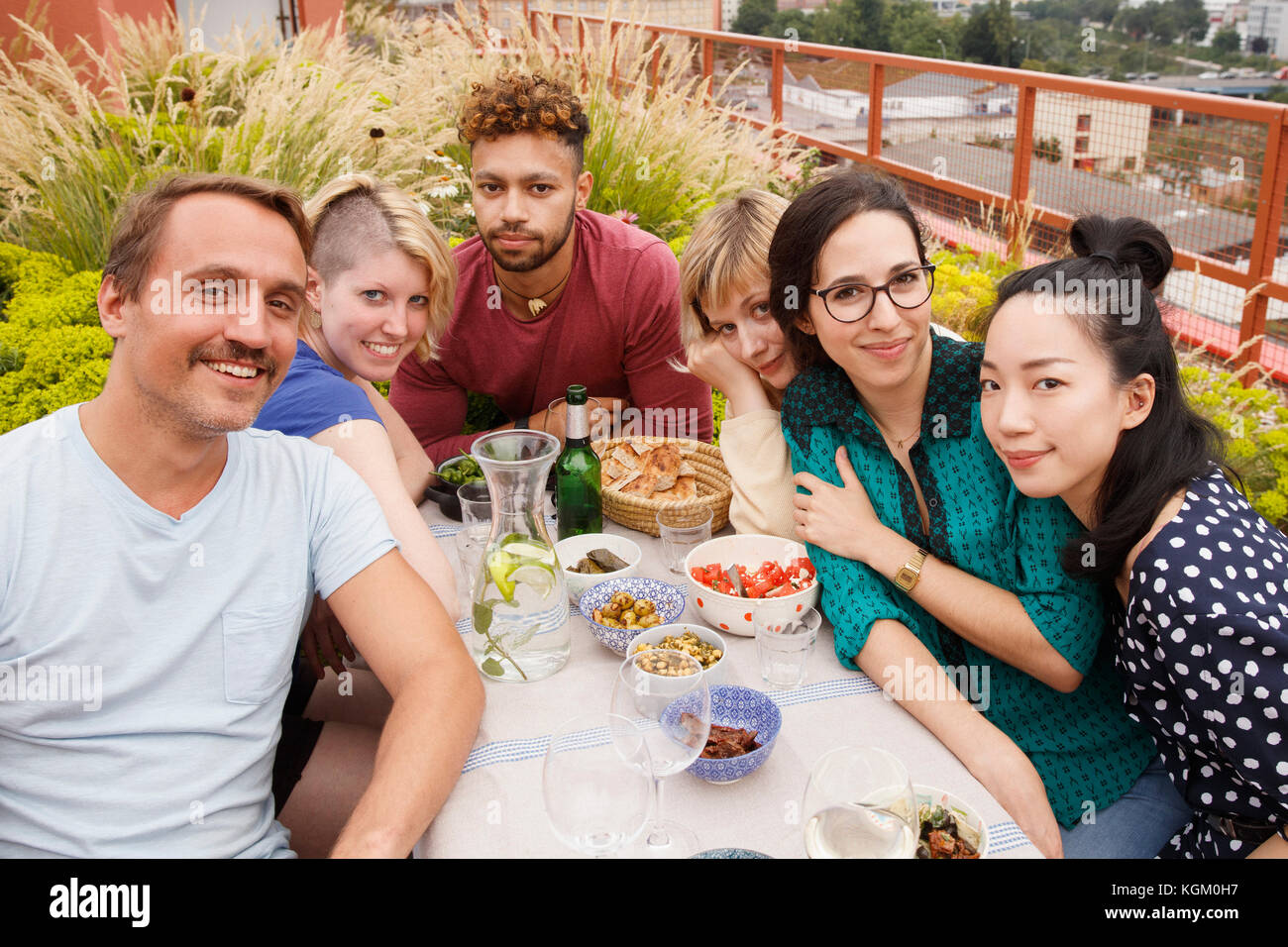 Portrait of happy male and female friends sitting at outdoor table at patio Stock Photo