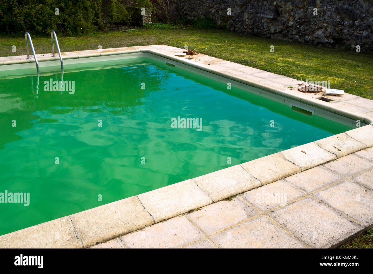 Starting the spring clean up of dead leaves and green algae in a swimming pool neglected over the winter Stock Photo