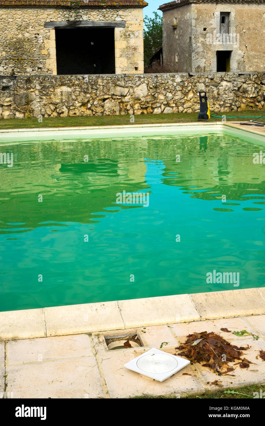 Starting the spring clean up of dead leaves and green algae in a swimming pool neglected over the winter Stock Photo