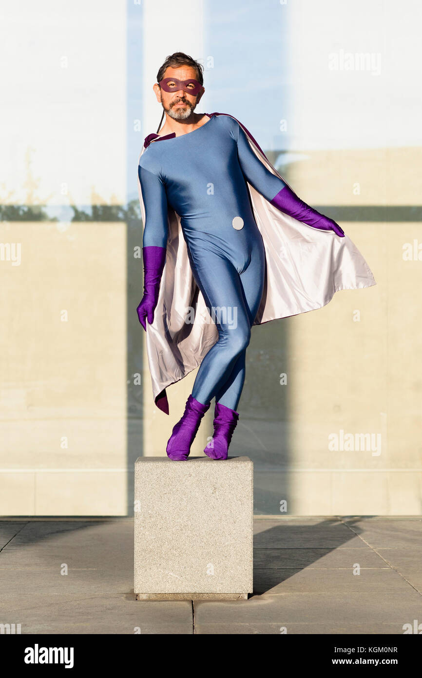 Portrait of superhero holding cape while standing on concrete against glass  wall Stock Photo - Alamy