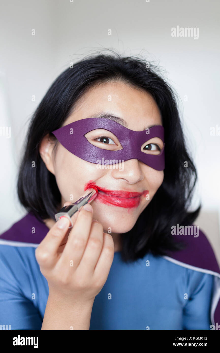 Portrait of smiling female superhero wearing red lipstick against gray background Stock Photo