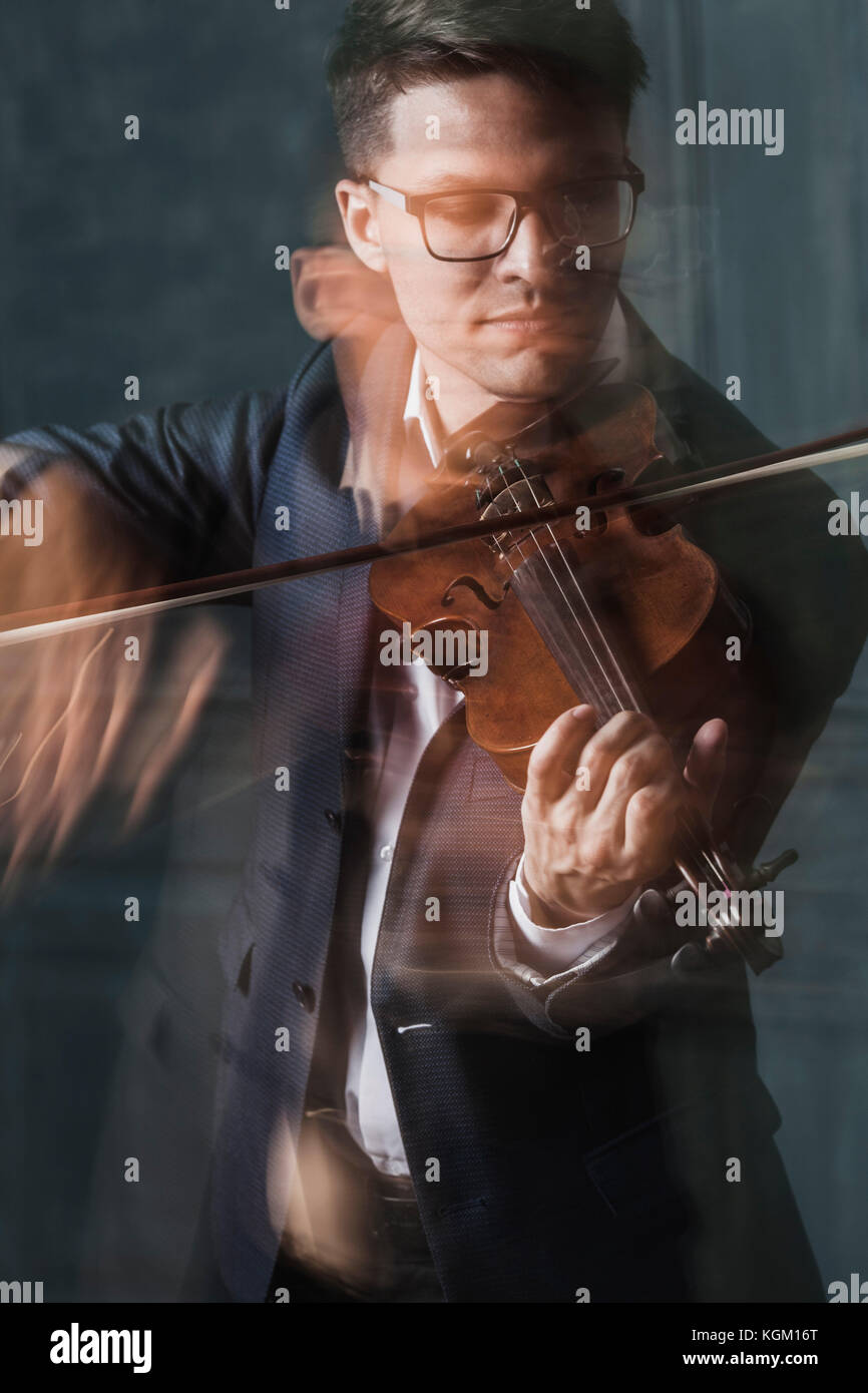 Blurred motion of violinist playing violin against wall Stock Photo