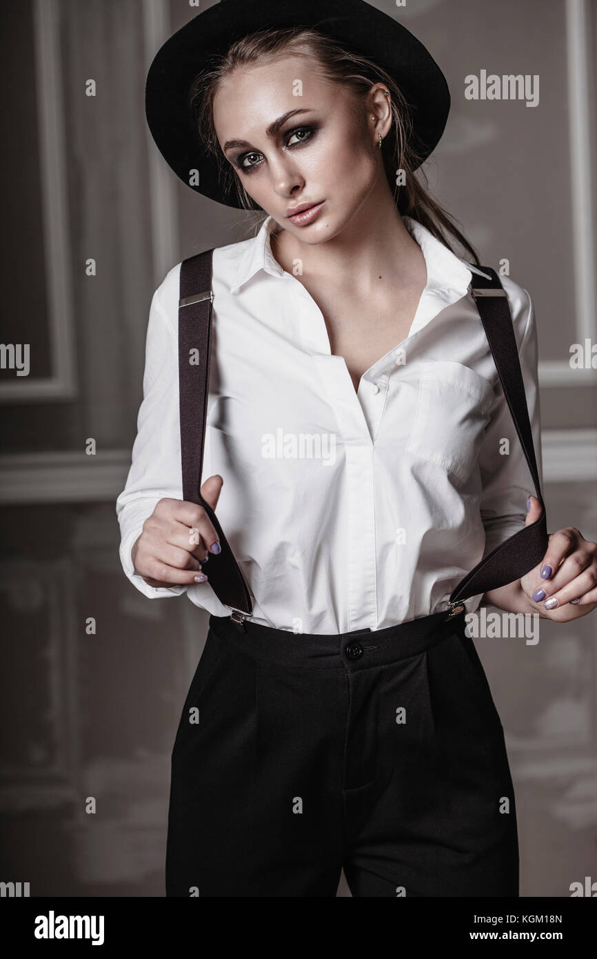 Portrait of young woman wearing suspenders standing against wall Stock  Photo - Alamy