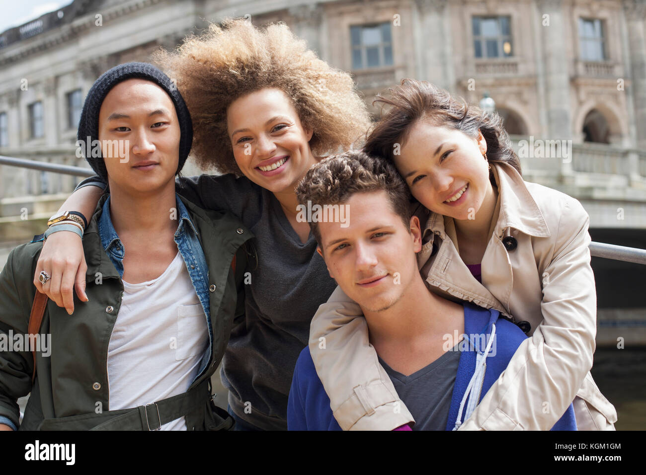 Low angle portrait of smiling young multi-ethnic friends against Bode Museum, Berlin, Germany Stock Photo