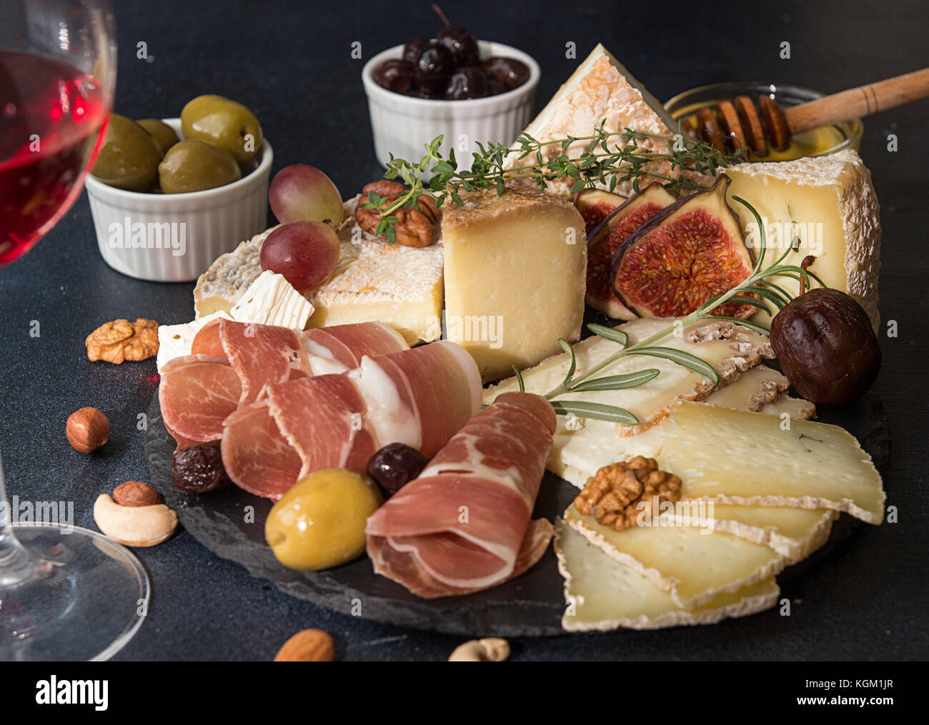 Glass of red wine and cheese plate with pieces moldy cheese, prosciutto