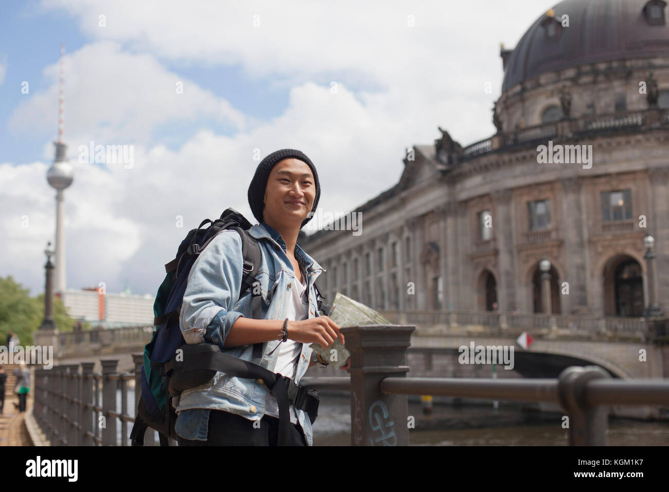 Smiling young male tourist standing with map by railing against Bode Museum, Berlin, Germany Stock Photo