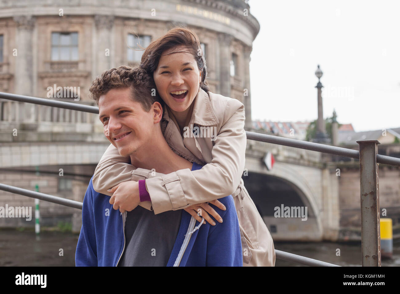 Low angle portrait of cheerful woman embracing male friend against Bode Museum, Germany Stock Photo