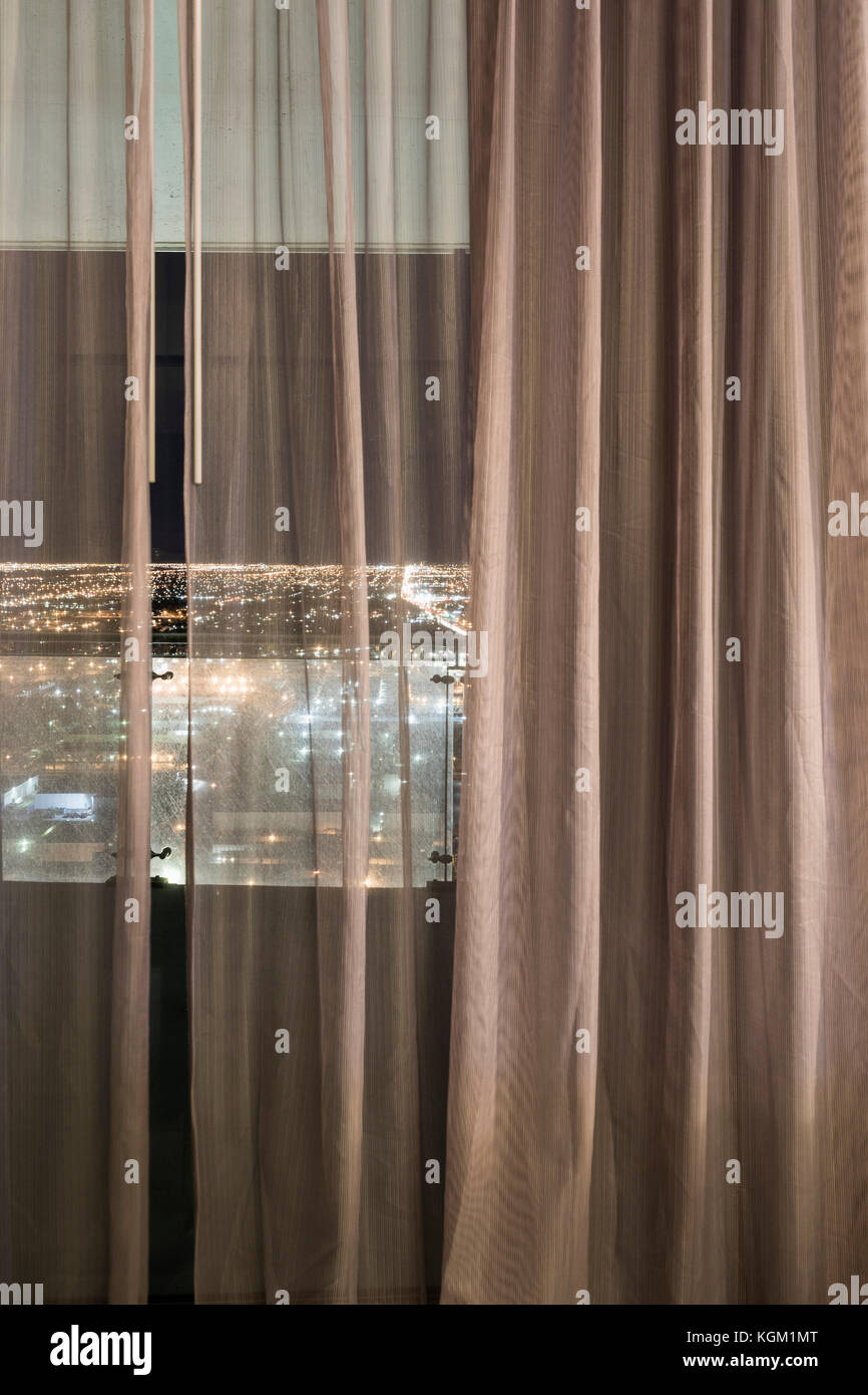 Illuminated city seen through curtains over window at night, Las Vegas, Nevada, USA Stock Photo