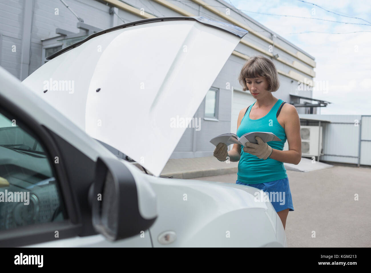 Mature woman reading manual while standing by breakdown car Stock Photo