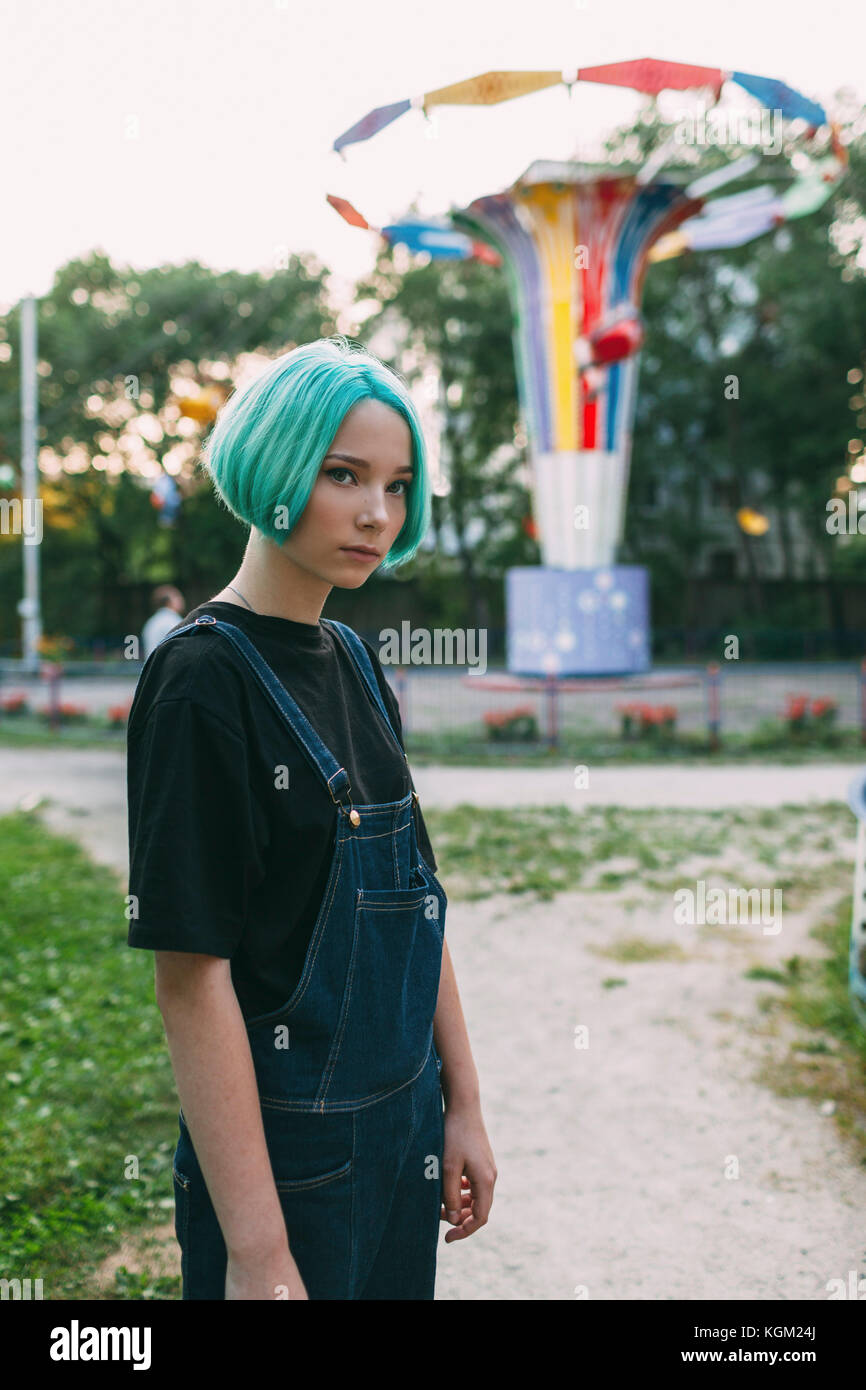 Portrait of teenage girl standing against amusement park ride Stock Photo