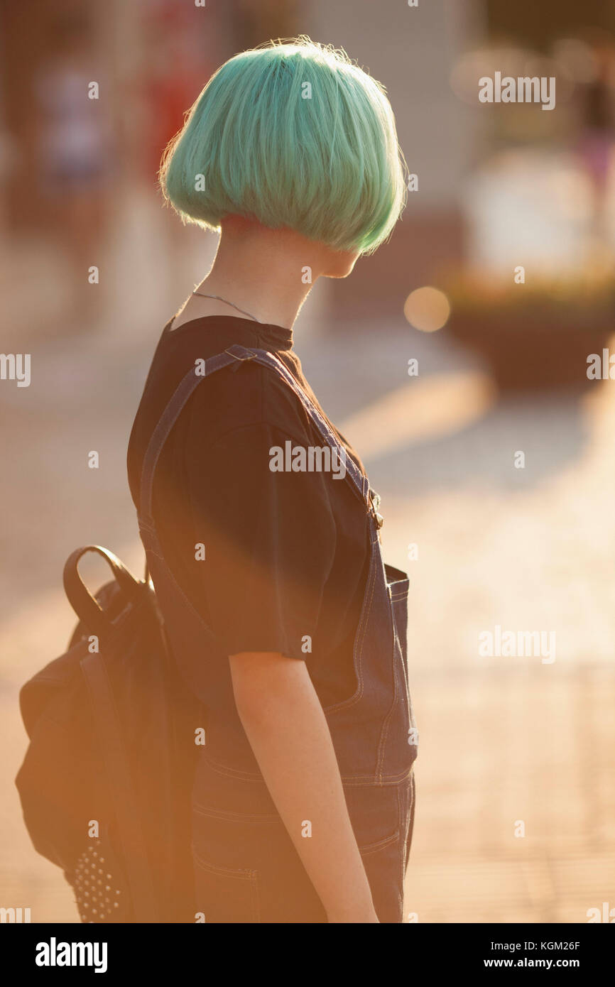 Teenage girl carrying backpack while standing in city during sunny day ...