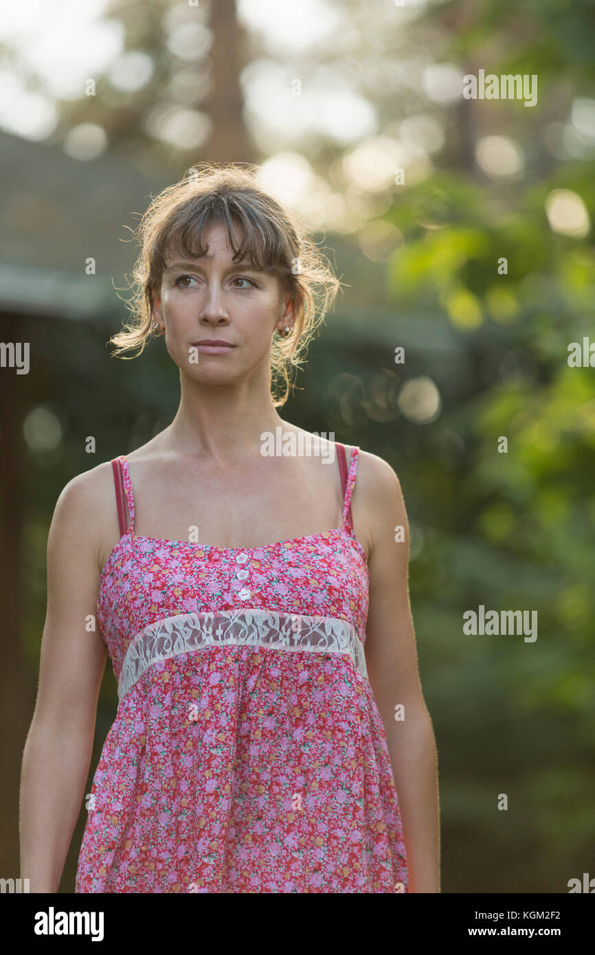 Thoughtful woman wearing pink dress standing in yard Stock Photo