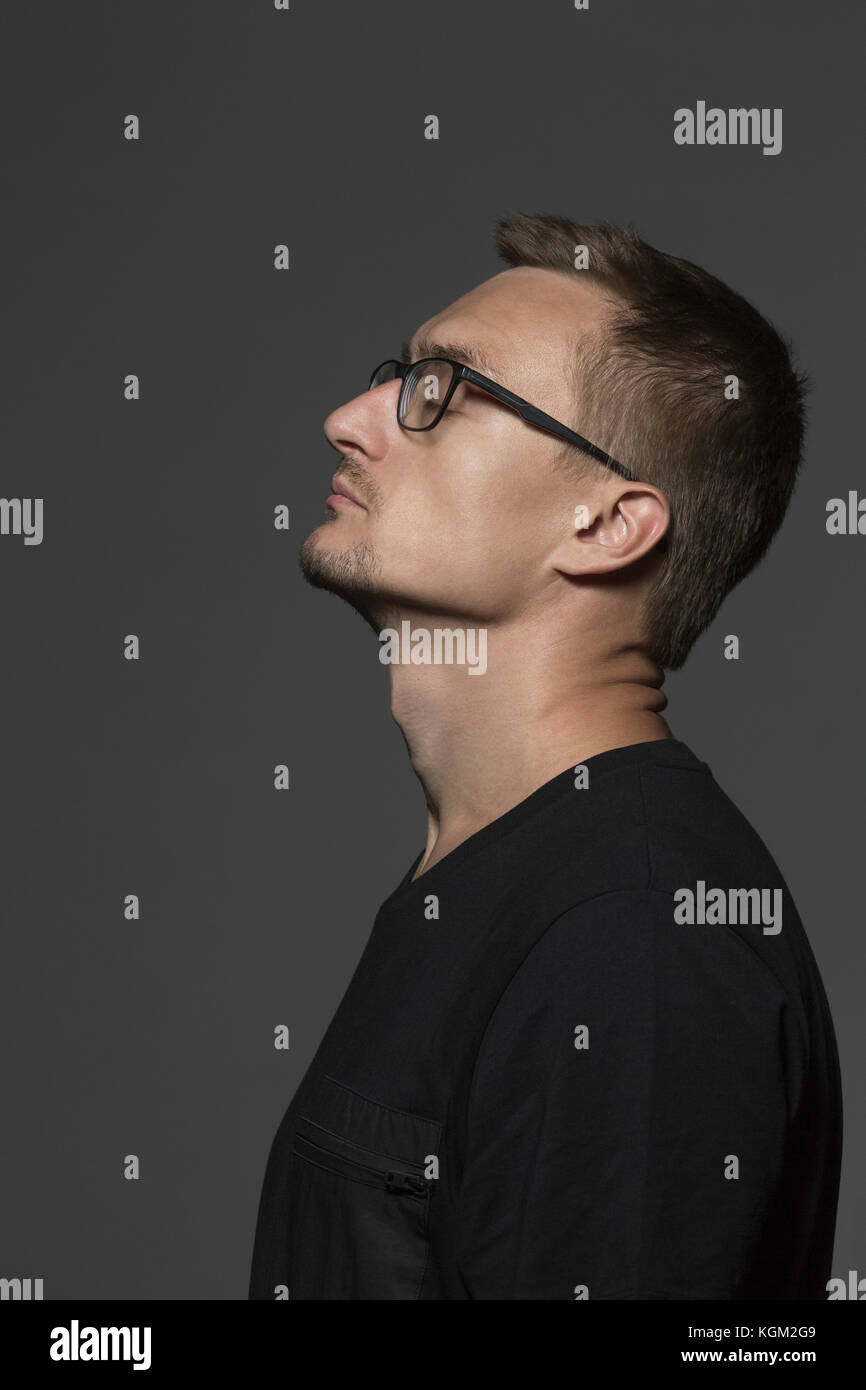 Side view of mid adult man standing with closed eyes against gray background Stock Photo